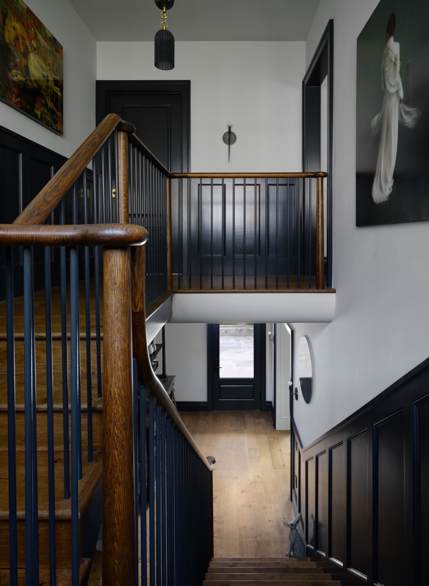 Wood staircase with dark painted paneling in a rehabilitated circa-1936 Austin house