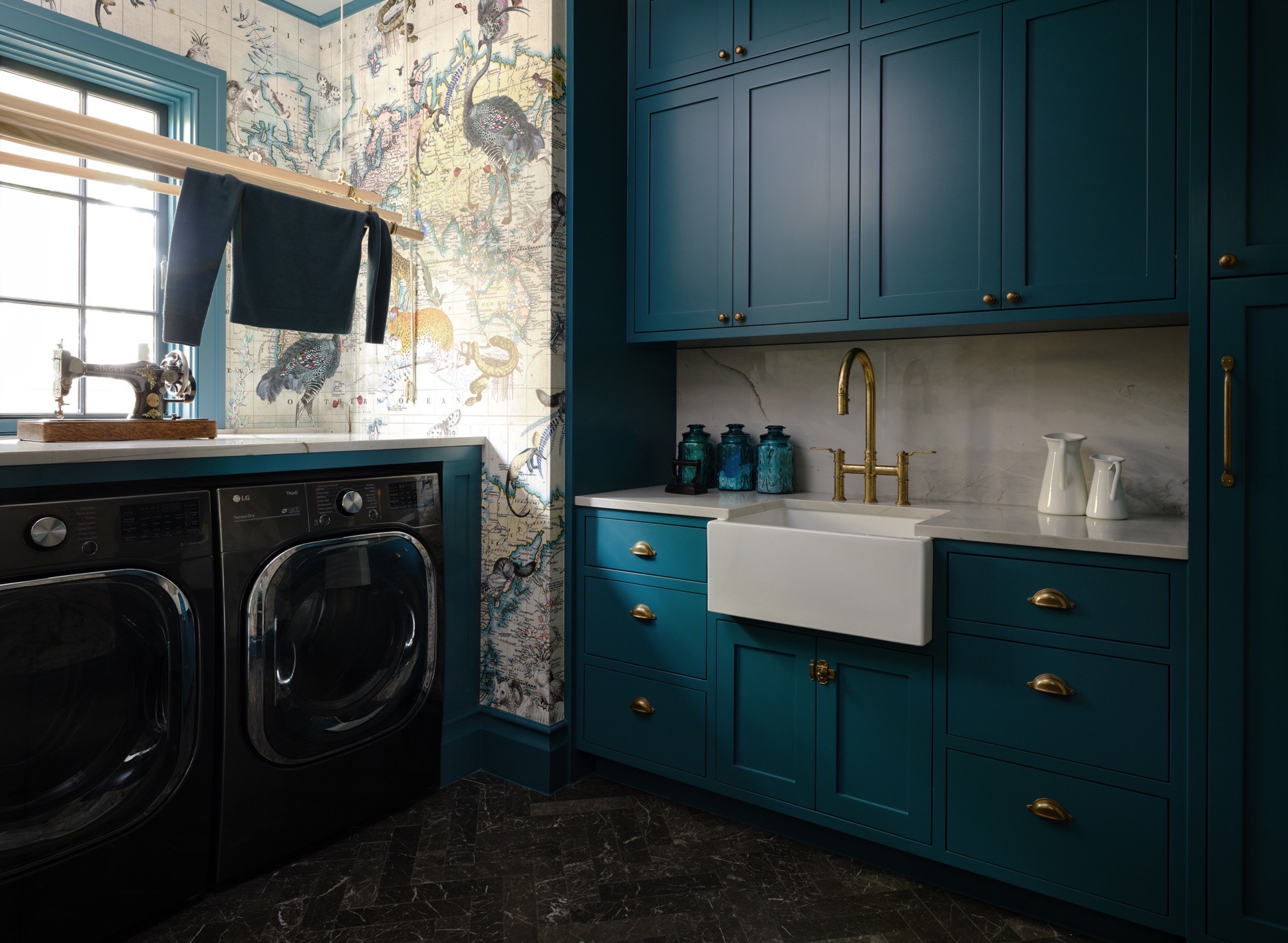 Blue laundry room with brass fixtures and patterned wallcovering in Austin