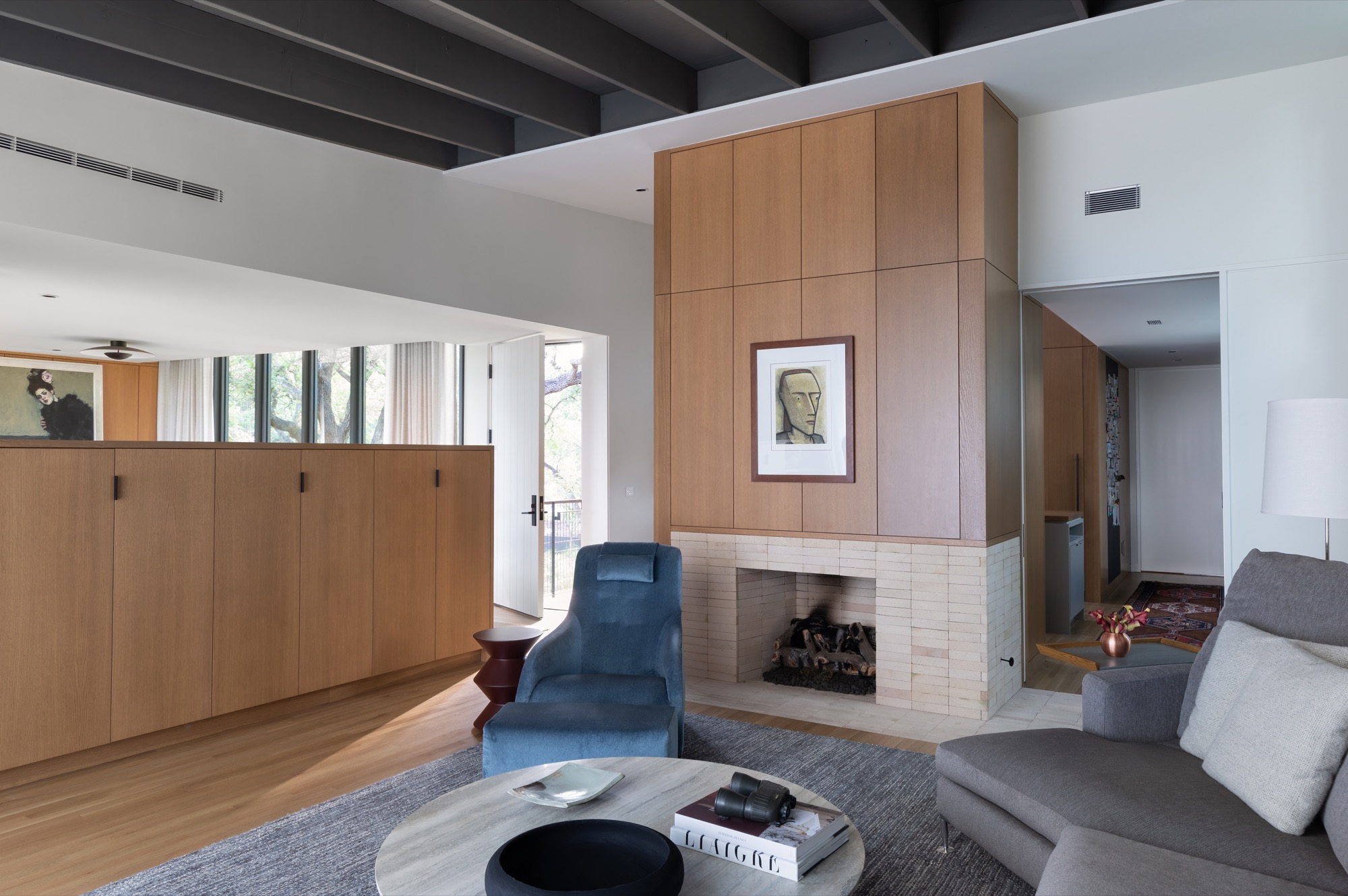 Living room of a modern Austin house with a white oak paneled wood-burning fireplace volume