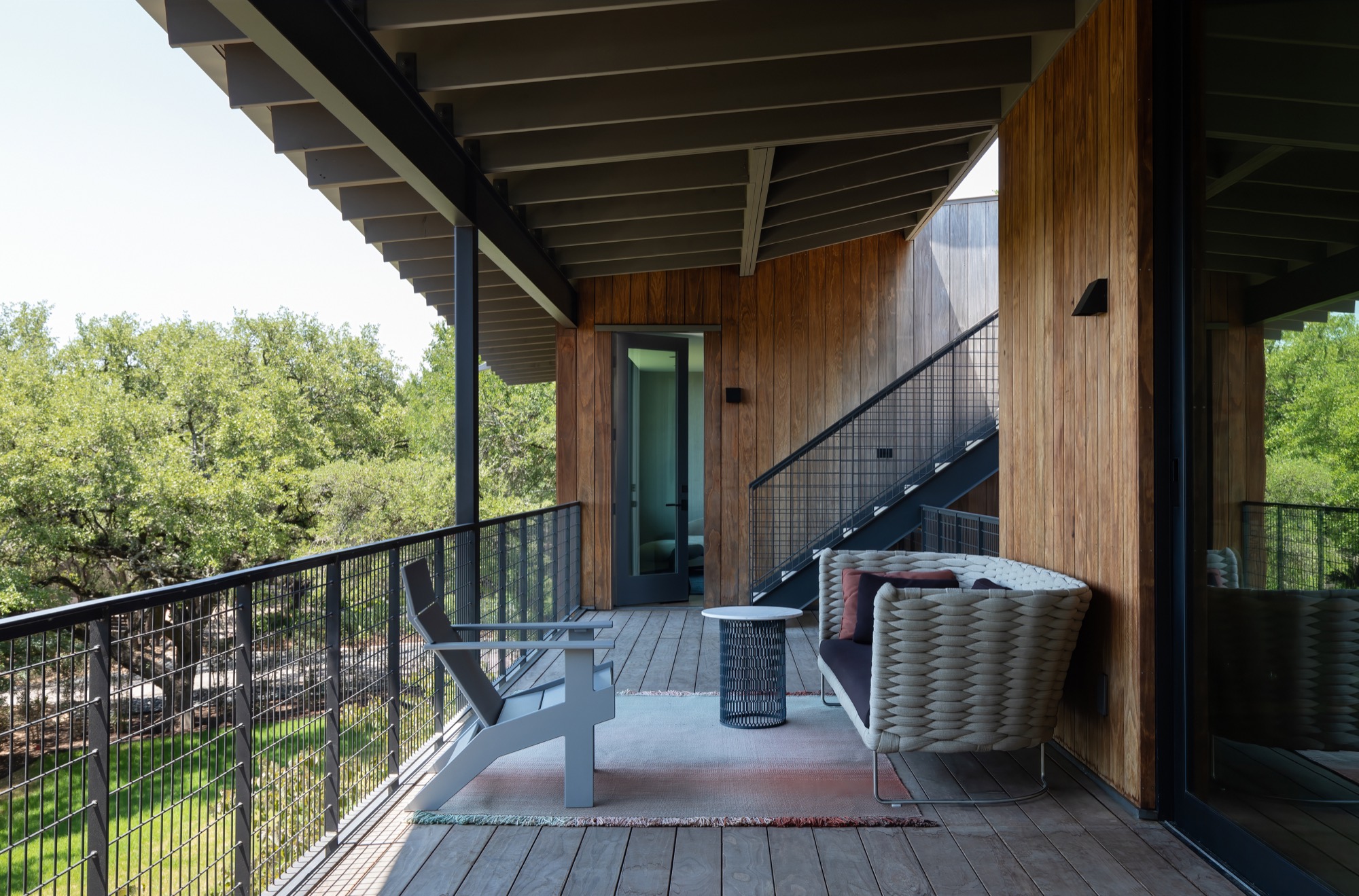 Covered terrace of a modern Austin house with wood cladding and outdoor seating